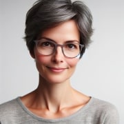 A woman with gray hair and glasses is posing for a photo.